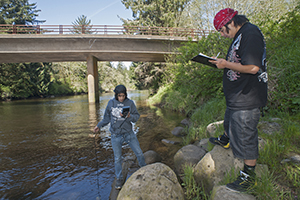 Gaspar Ramos, 16, watches the meter on the datasonde, a water quality measurement tool that gives information about factors such as temperature, salinity and dissolved oxygen, while Jonah Black, 19, records the results on the Dickey River near LaPush. The two students receive high school science credit doing work through the North Olympic Skills Center Natural Resources program in cooperation with Quileute Natural Resources and the Quileute Tribal School.